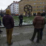 Jake Schneider talking to a group standing in a circle on the sidewalk at a snowy Rosa-Luxemburg-Platz