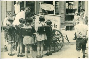 A group of children with backpacks around an ice cream stand